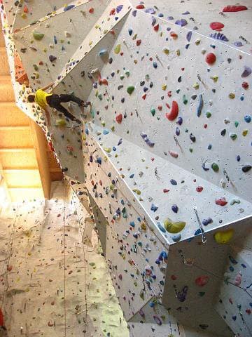 Kletterer an einer Indoor-Kletterwand mit bunten Griffen im DAV-Kletterzentrum Stuttgart.