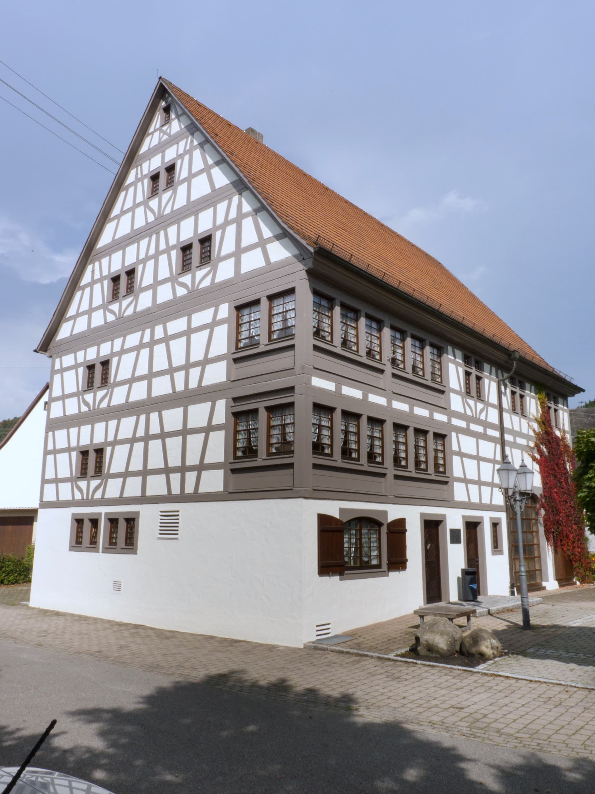 Großes, saniertes historisches Fachwerkgebäude in weiß mit grauem Fachwerk und spitzem Giebelk