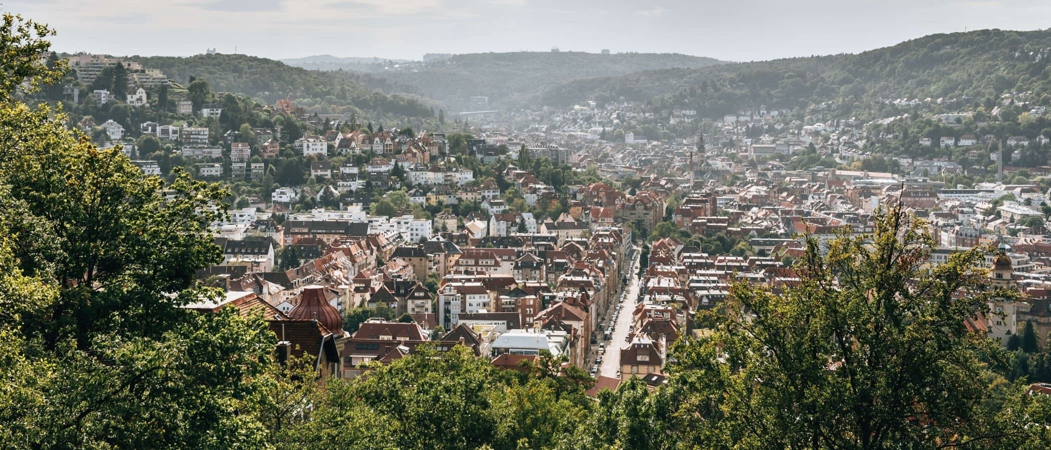 Panoramablick auf Stuttgart vom Weißenburgpark aus, mit vielen Häusern und grünen Hügeln im Hintergrund.
