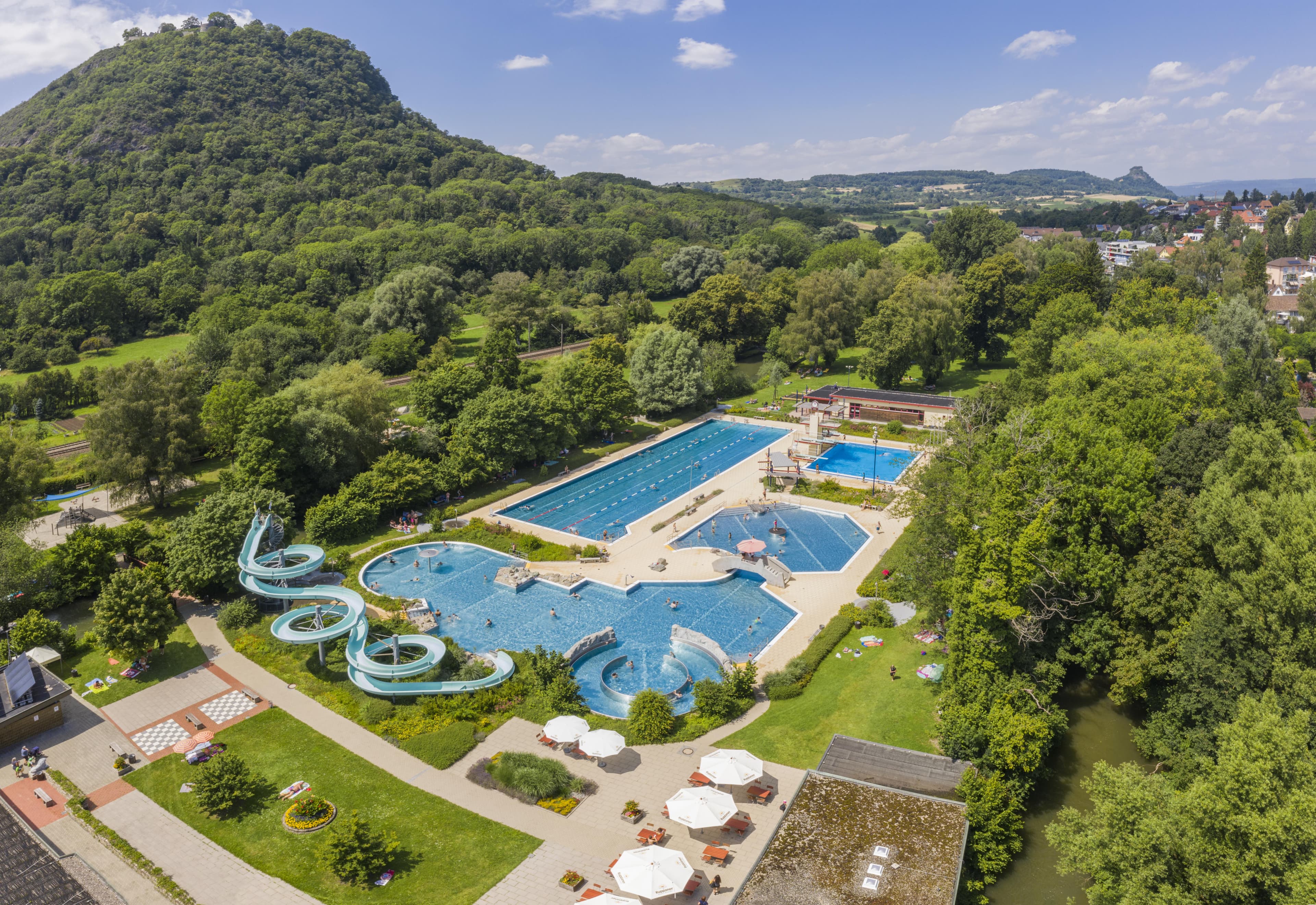 A large leisure park with several swimming pools and slides surrounded by green countryside.