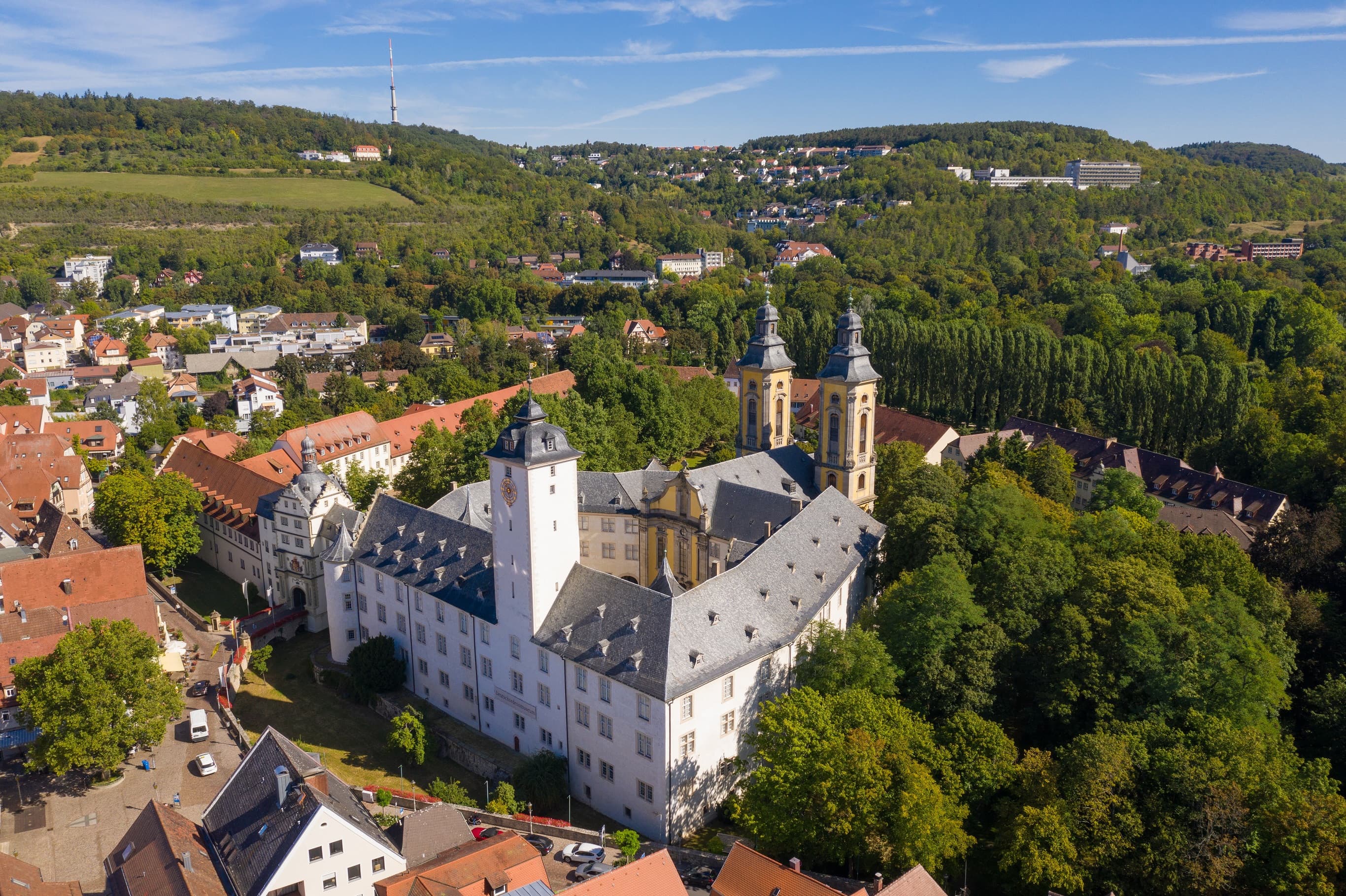Luftaufnahme vom Residenzschloss Mergentheim. Man sieht den Schlosshof mit den Kirchtürmen, der Schlosspark im Hintergrund