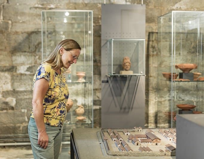 Eine Frau steht vor einer Vitrine mit römischen Funden