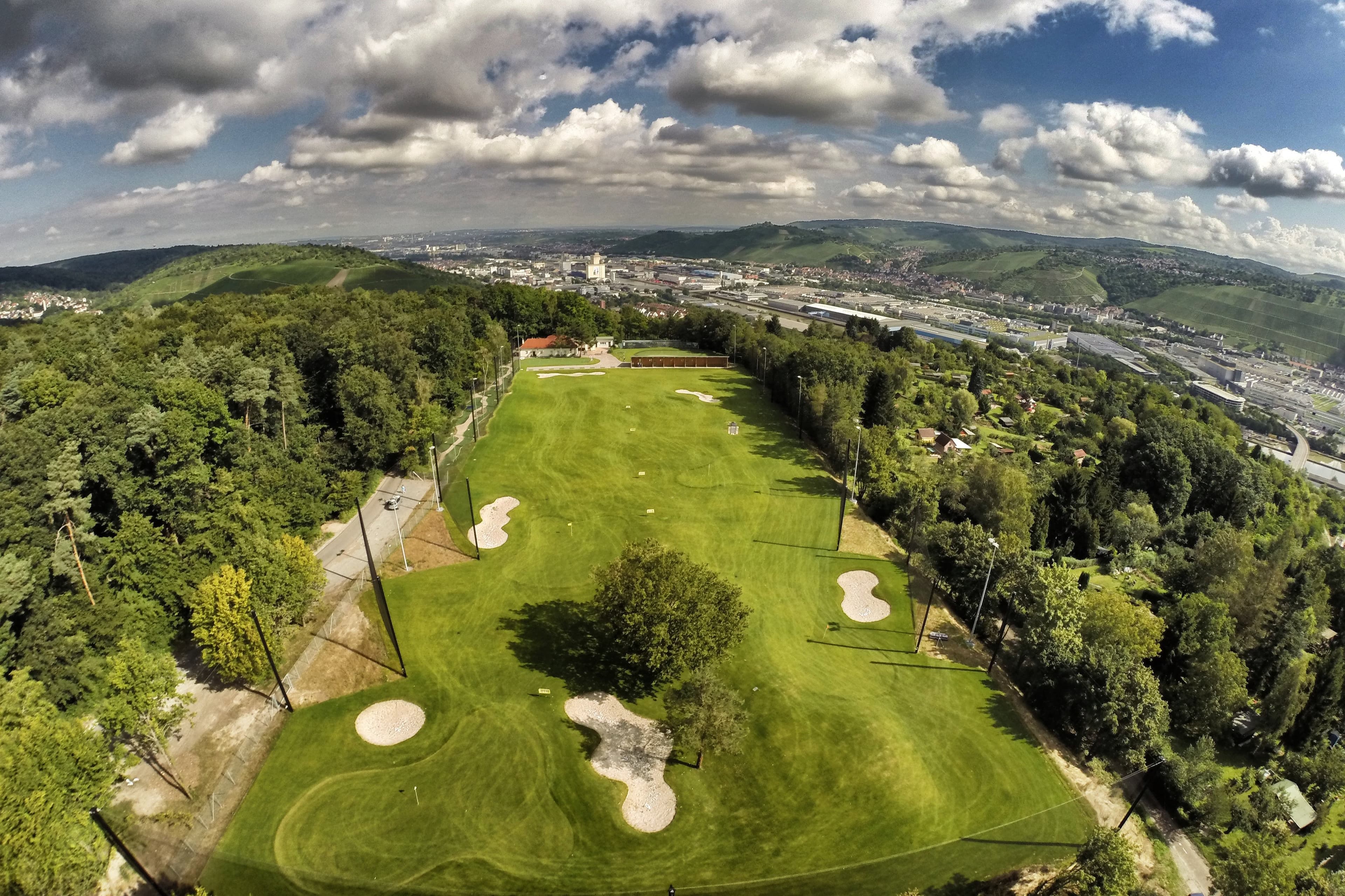 Luftaufnahme eines Golfplatzes in Stuttgart mit umliegender Landschaft und Stadt im Hintergrund.