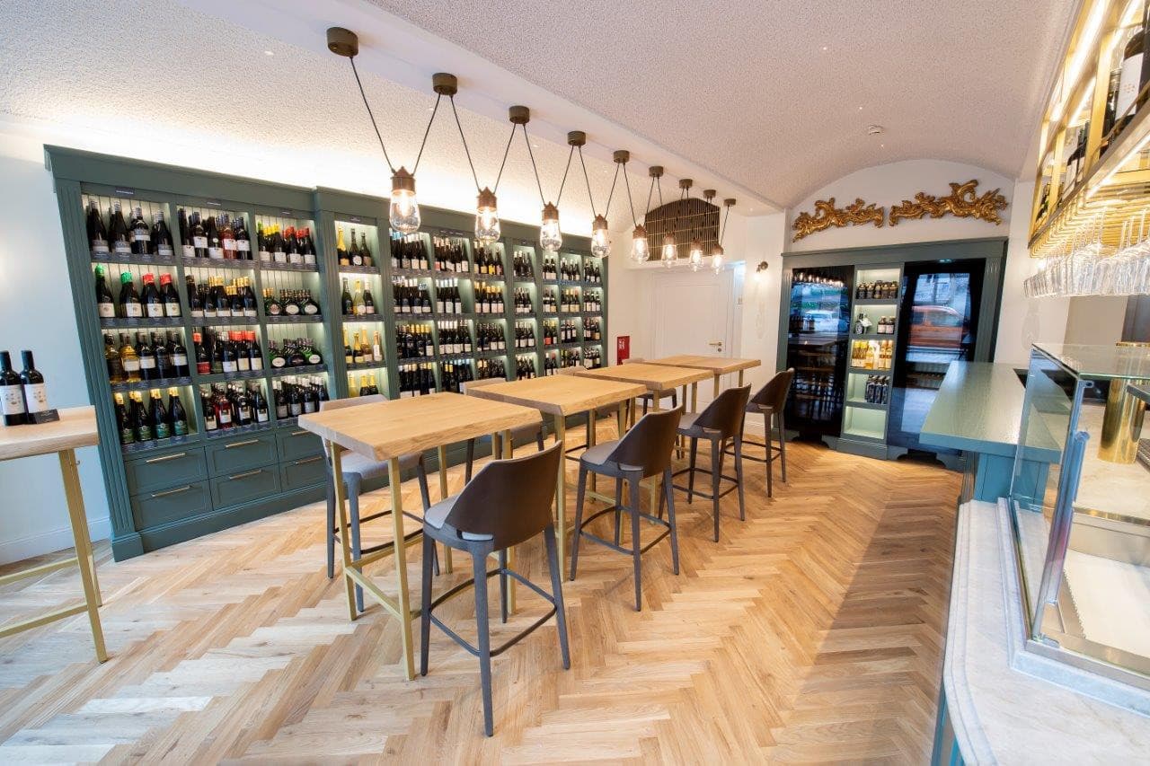 In der Vinothek gibt es Tische und Stühle, an der Wand stehen große Flaschenregale