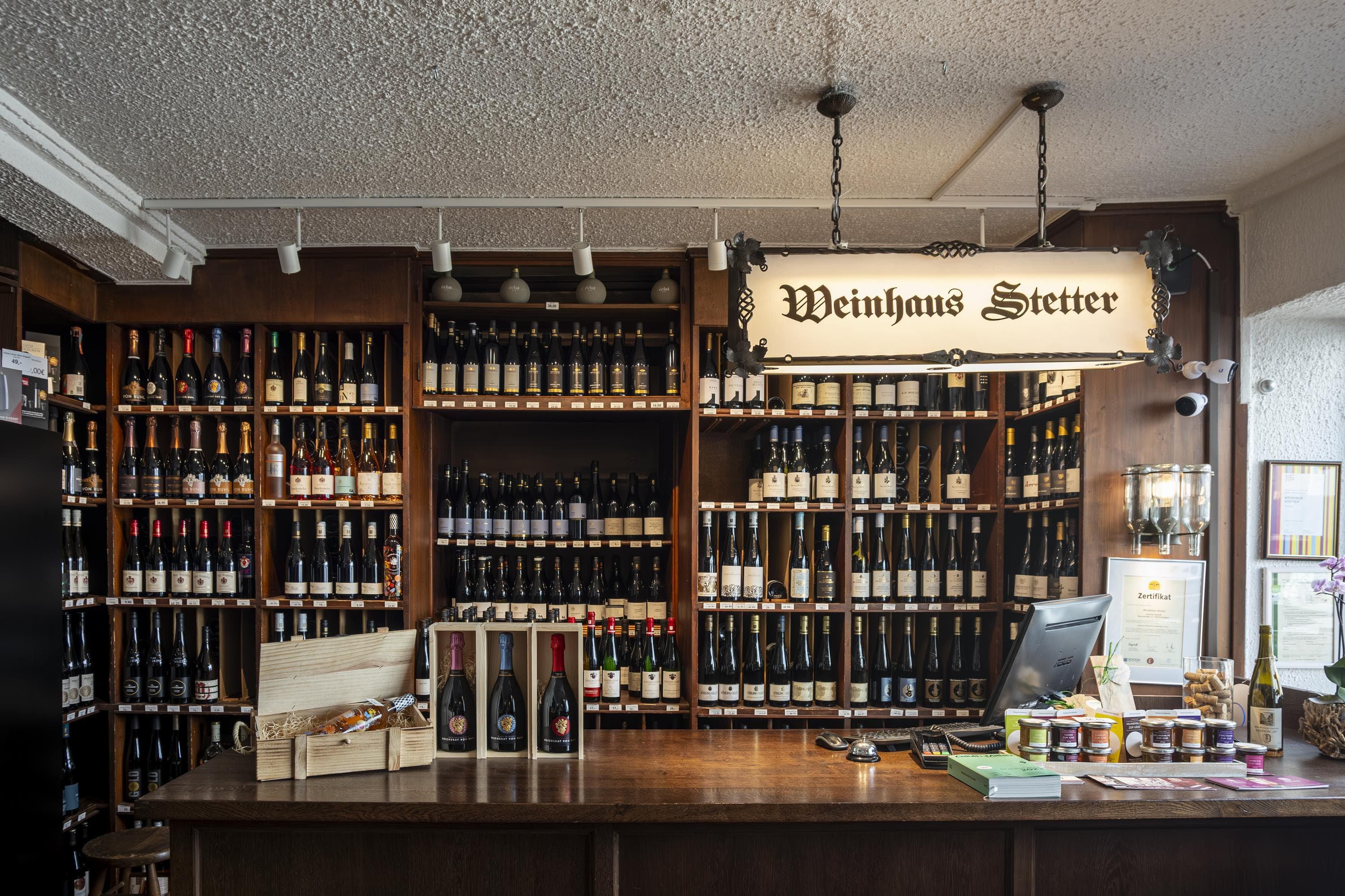 Innenansicht eines Weinladens mit Theke und Regalen voller Weinflaschen.