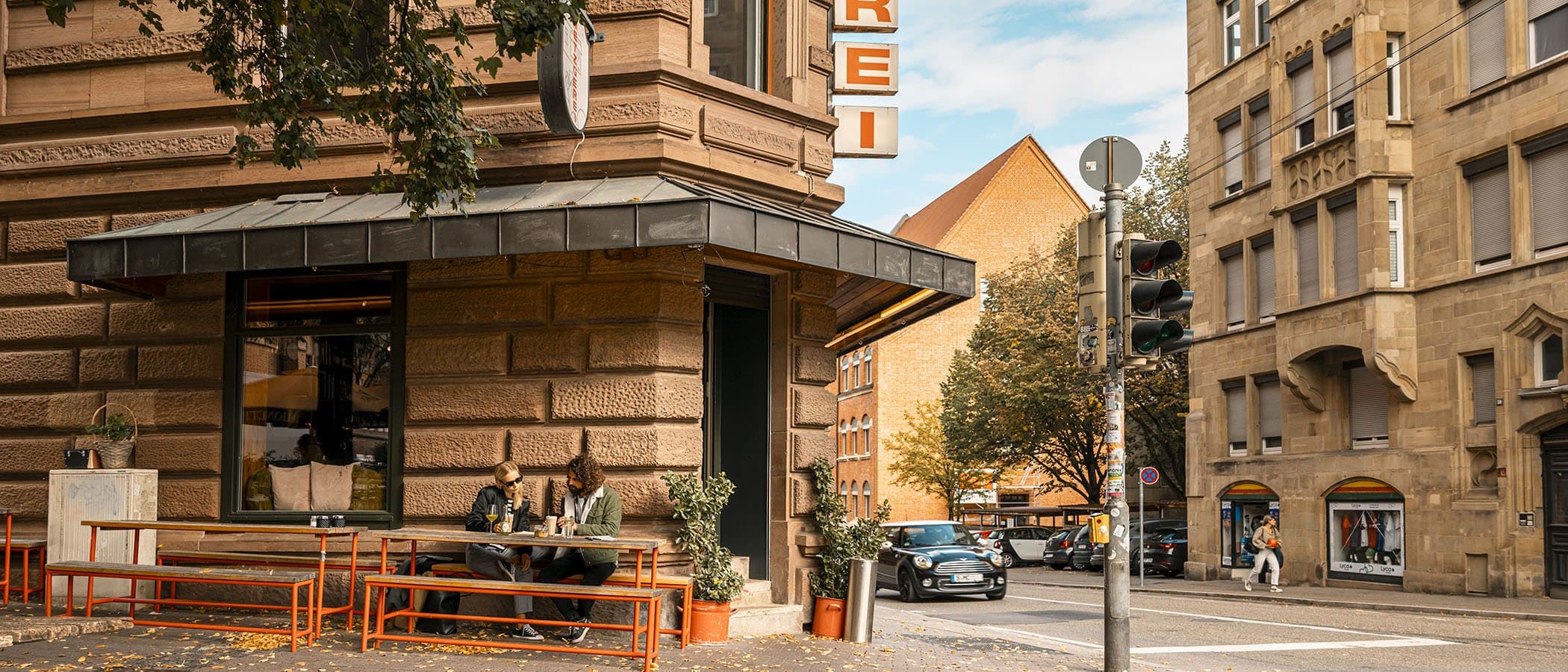 Straßenszene mit Metzgerei und Menschen an einem Tisch.