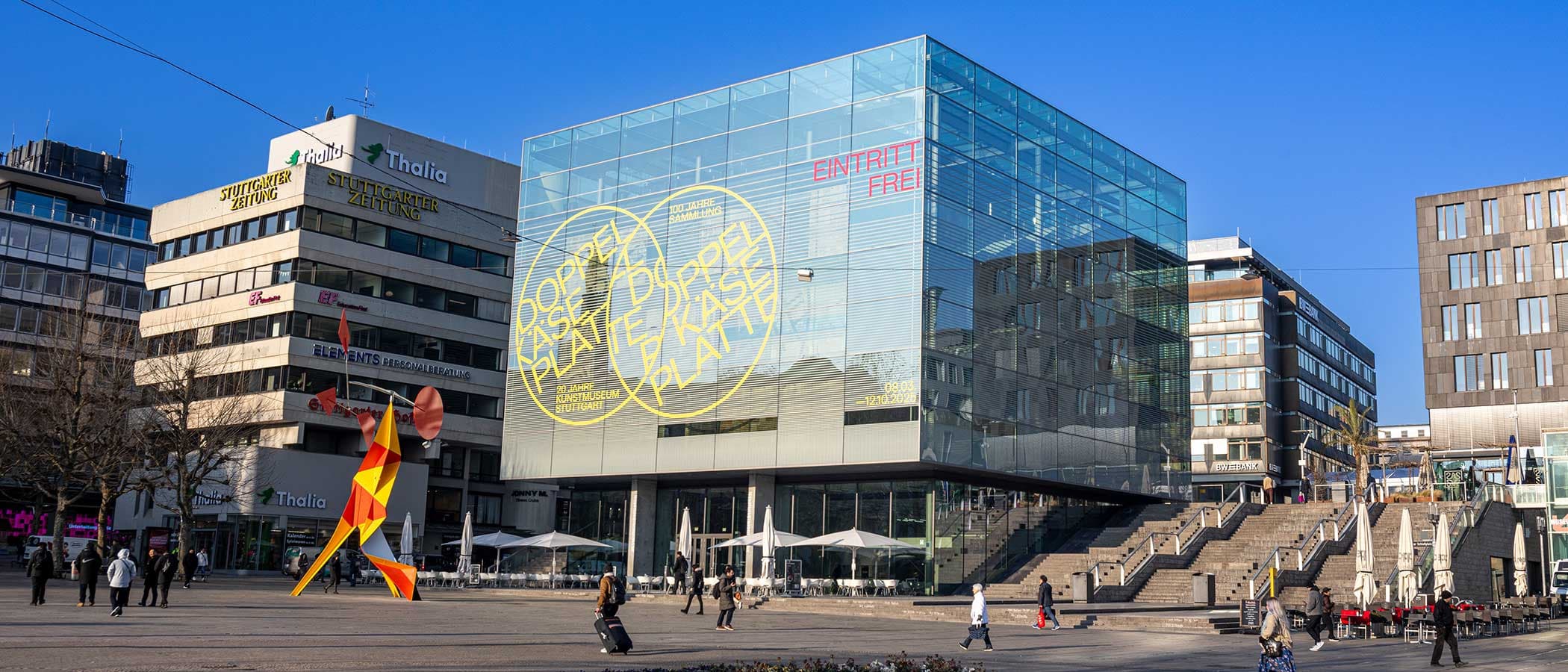 Kunstmuseum Stuttgart mit Glaskubus und moderner Skulptur auf dem Schlossplatz.