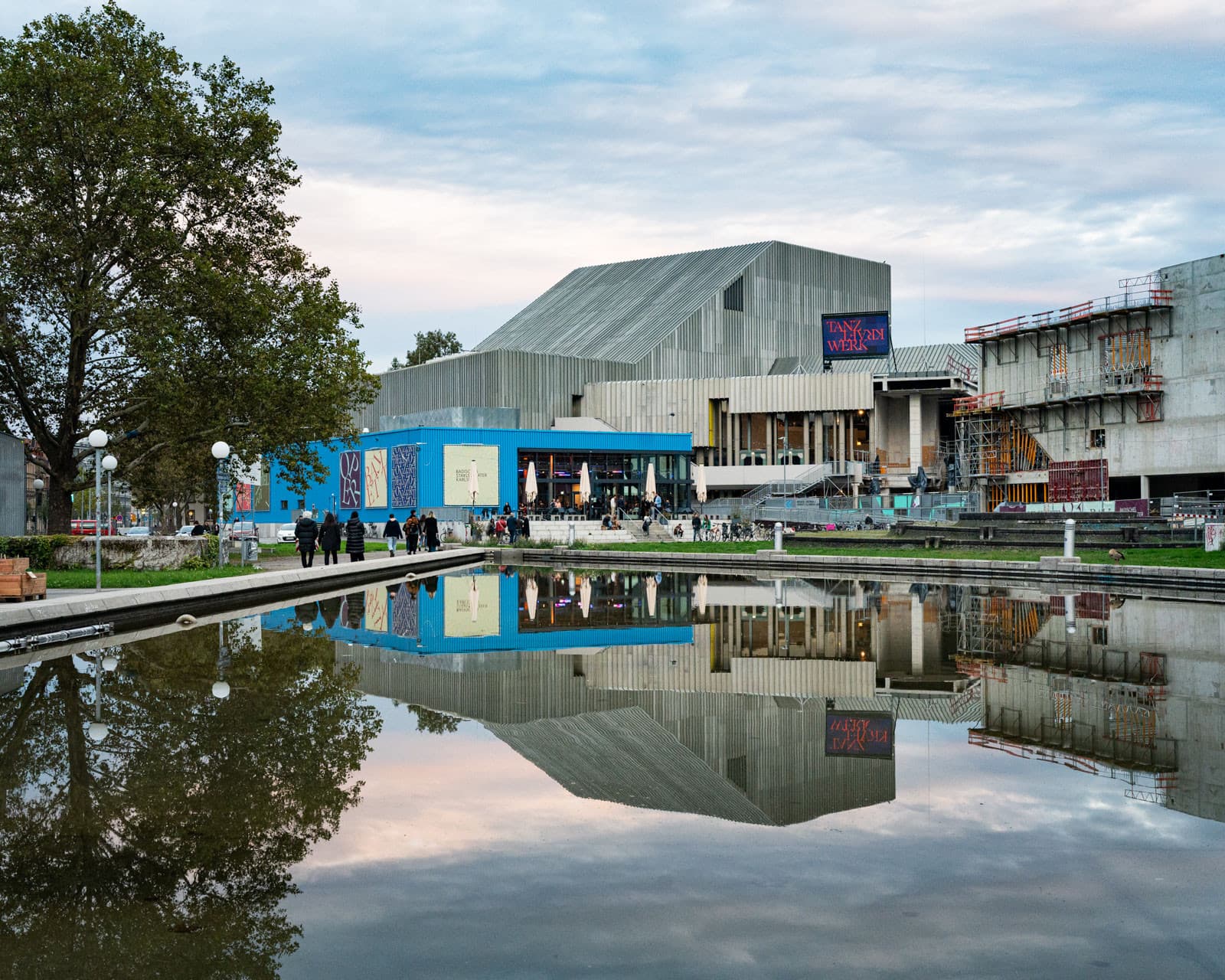 Modern theater building with a reflective water basin in front.