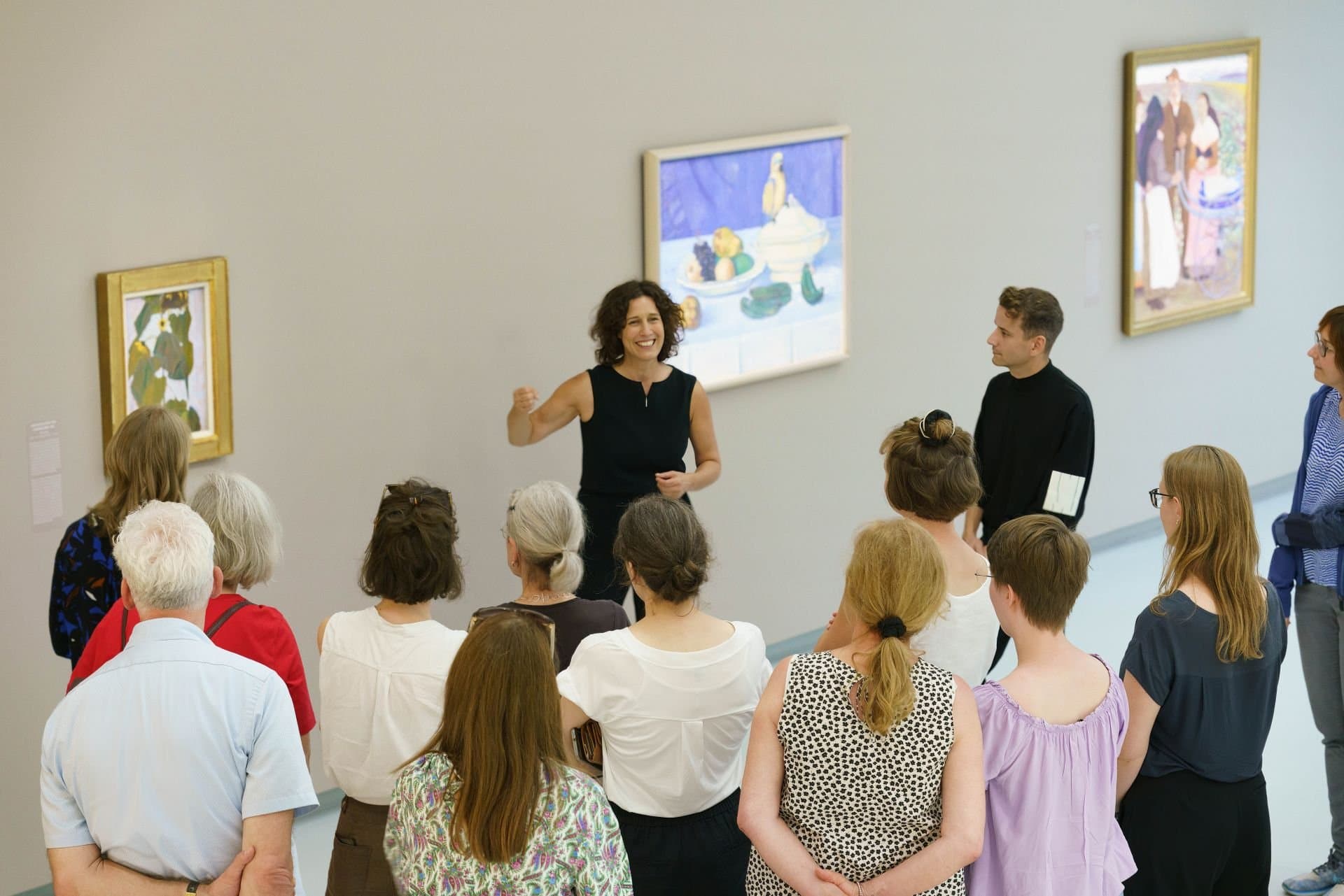 Die Direktorin der Kunsthalle erläutert einer Gruppe von Zuhörern die Bilder an der Wand.