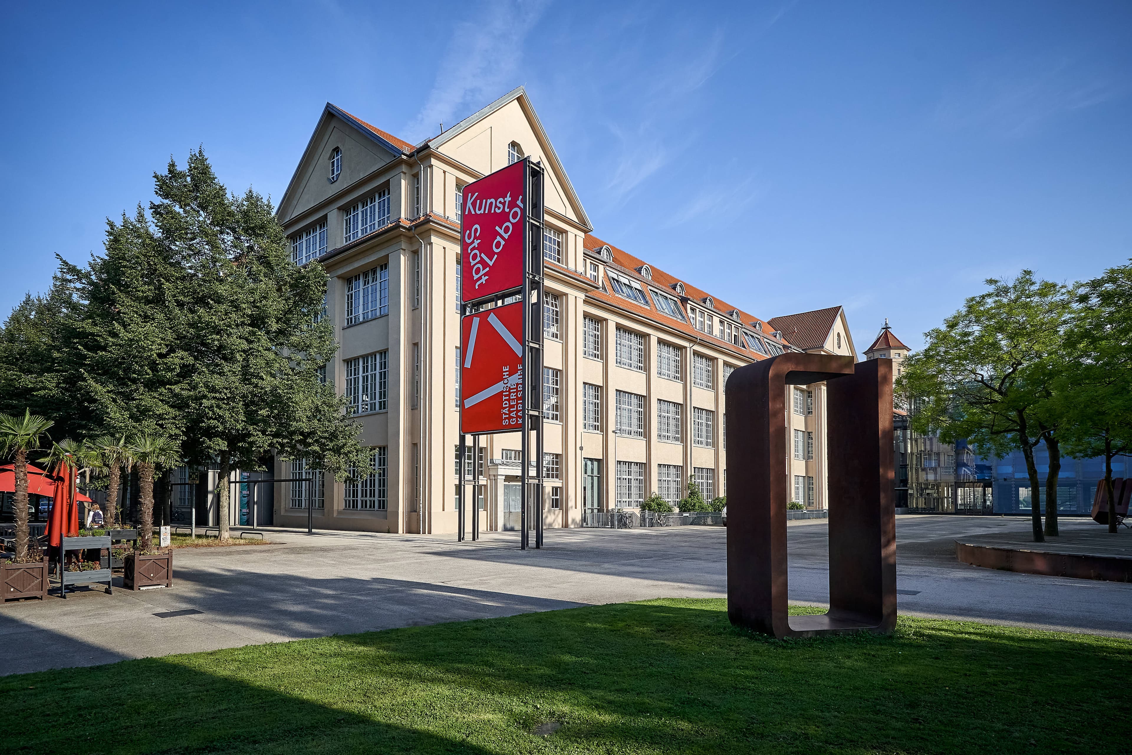 Gebäude des Kunstmuseums Karlsruhe, früher Städtische Galerie, mit einer grünen Wiese und abstraktem Kunstwerk davor