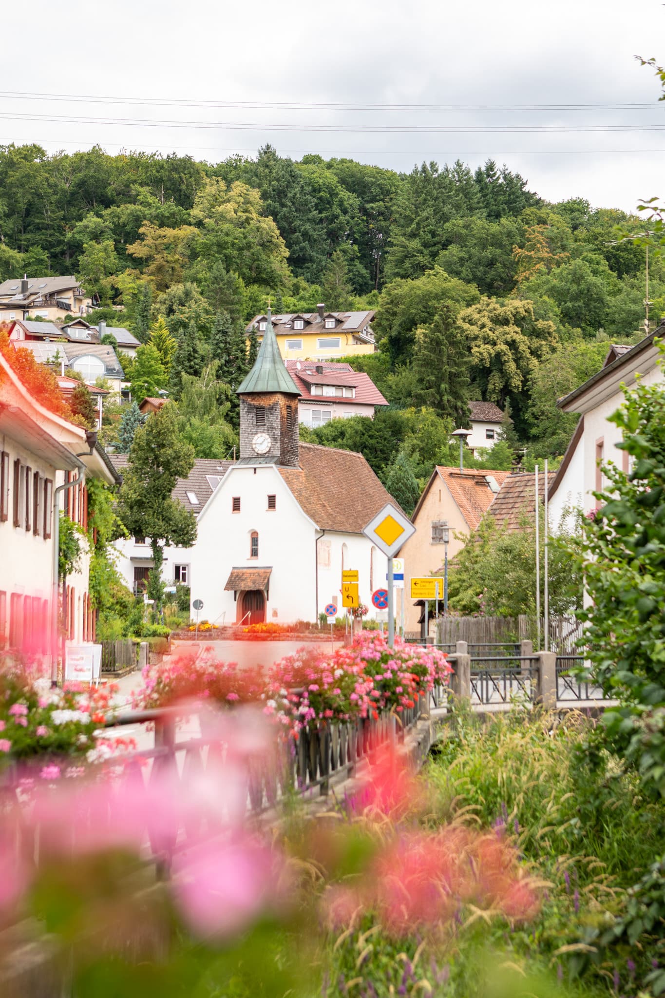 Kirche in Riedlingen mit blühenden Blumenampeln entlang der Straße.