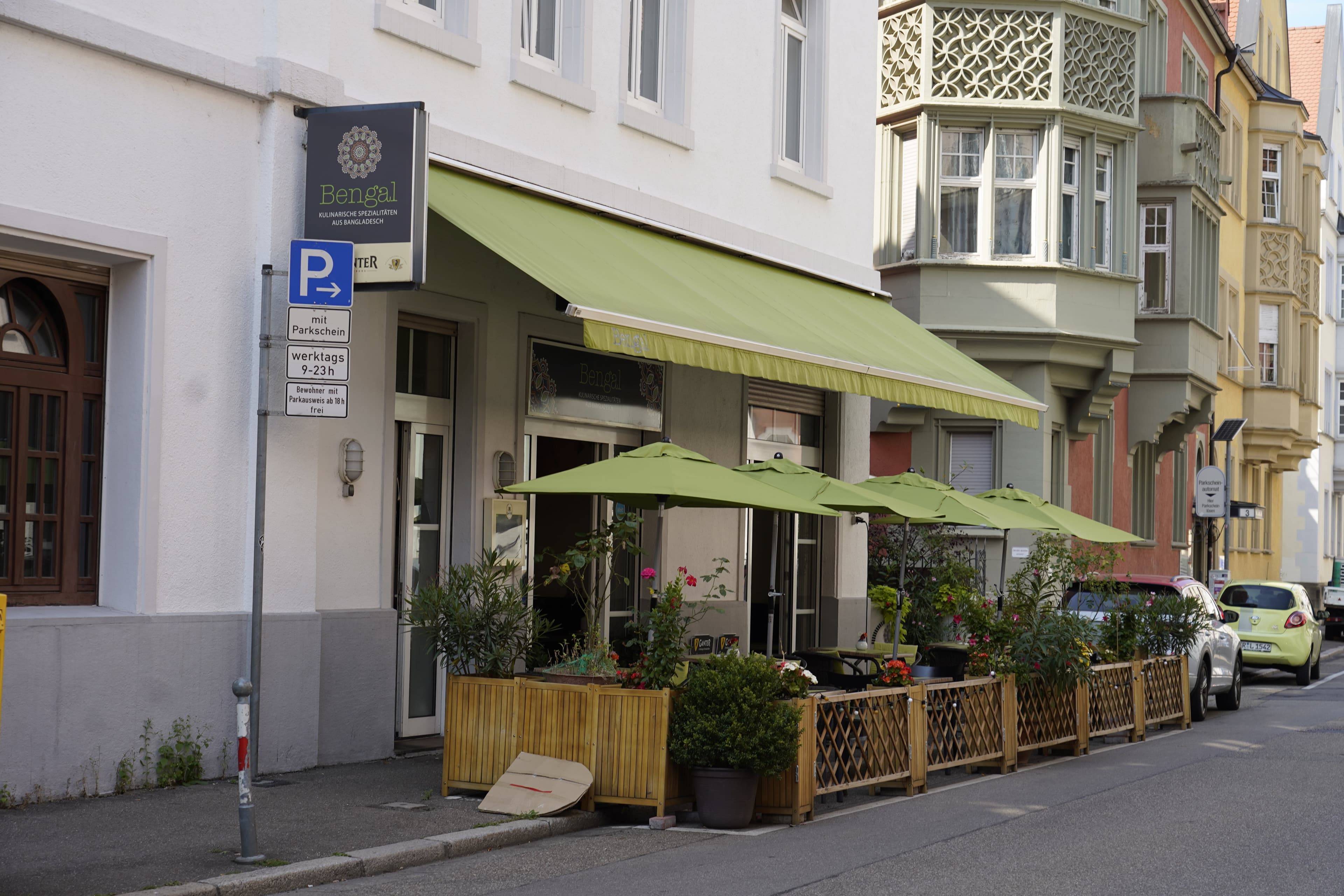 Straßenszene mit Restaurant Bengal und grünen Sonnenschirmen.
