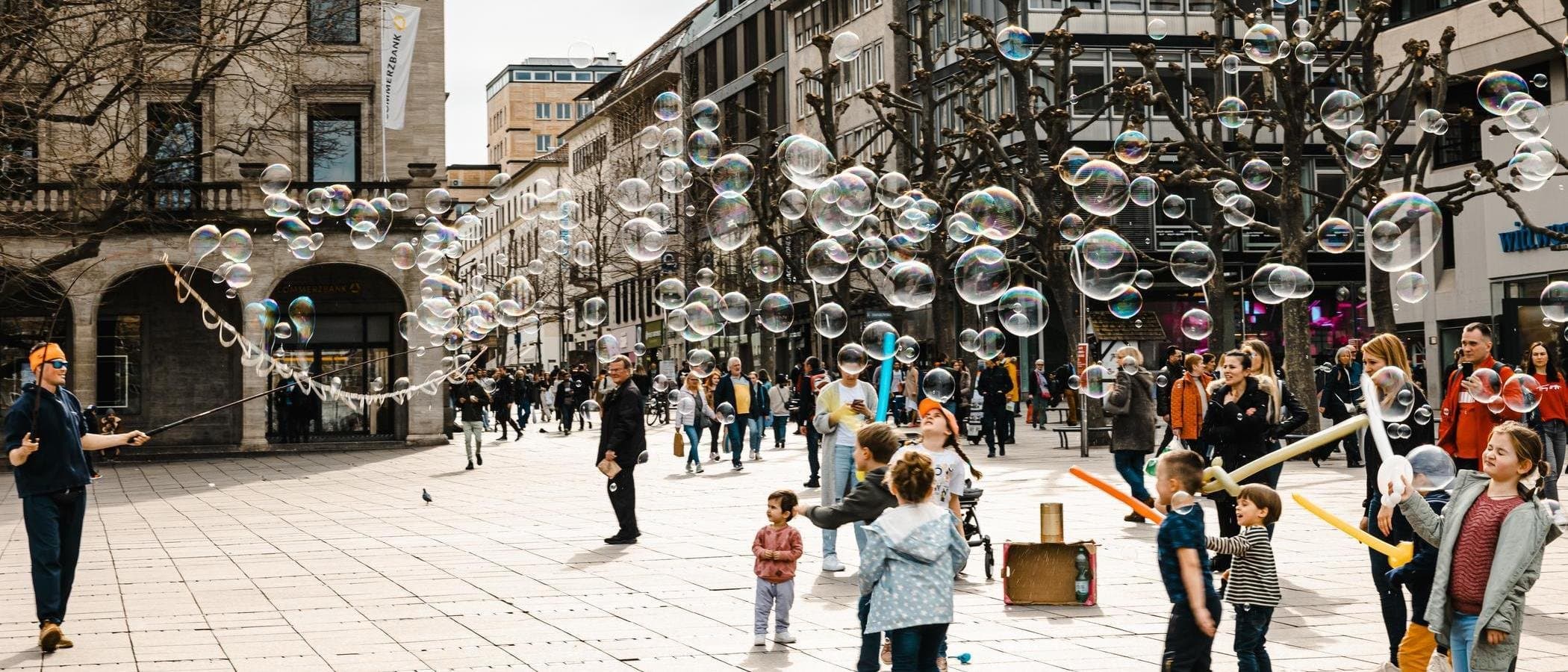 Straßenszene mit Seifenblasen und spielenden Kindern.