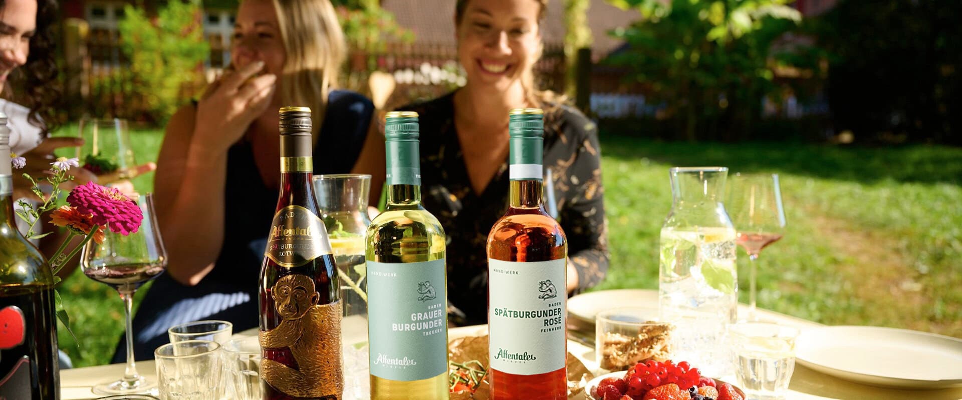 Table set with wines and snacks. In the background 3 people