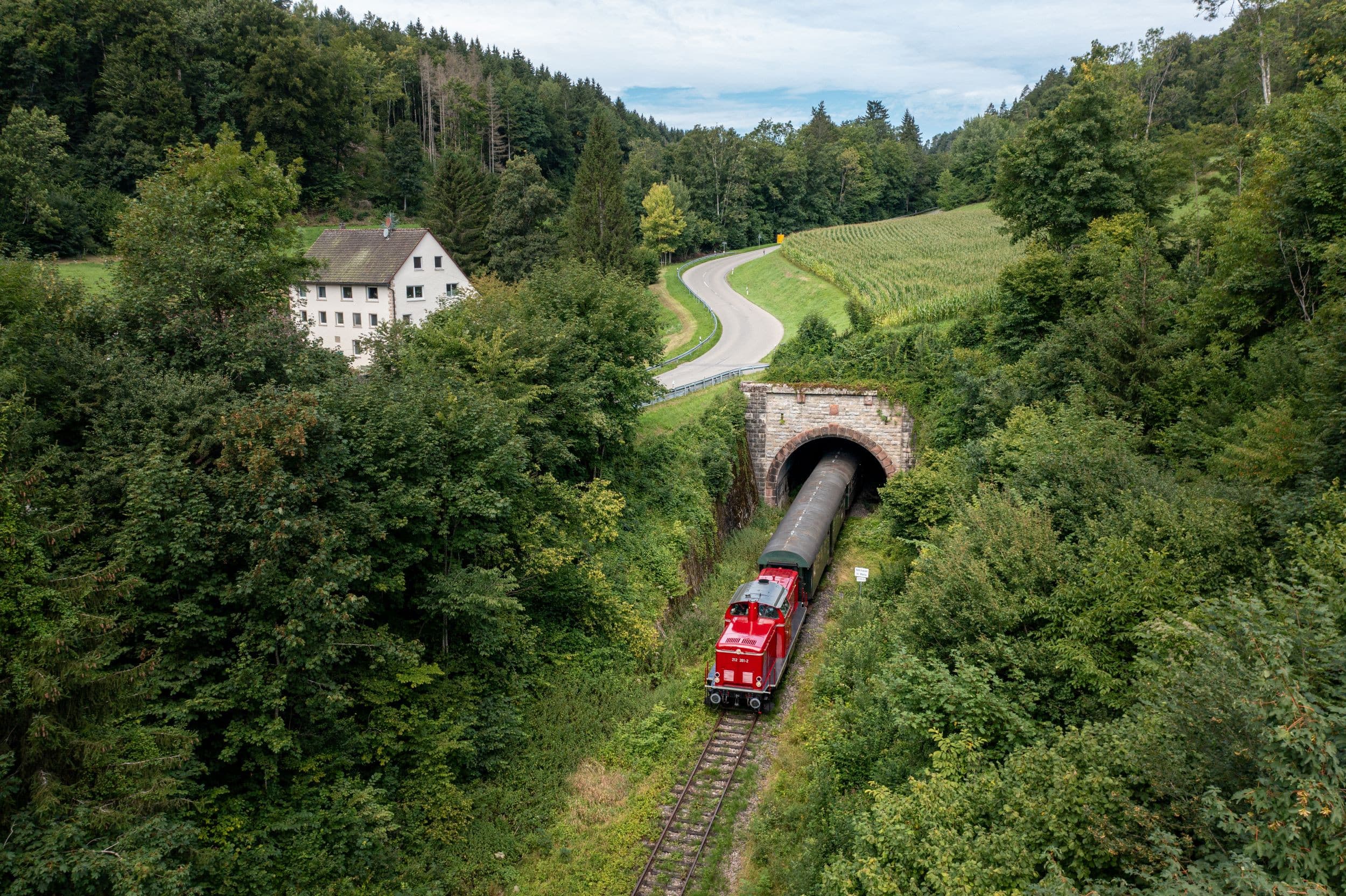 Rote Diessellok V100 der Sauschwänzlebahn aus  Tunnel kommend