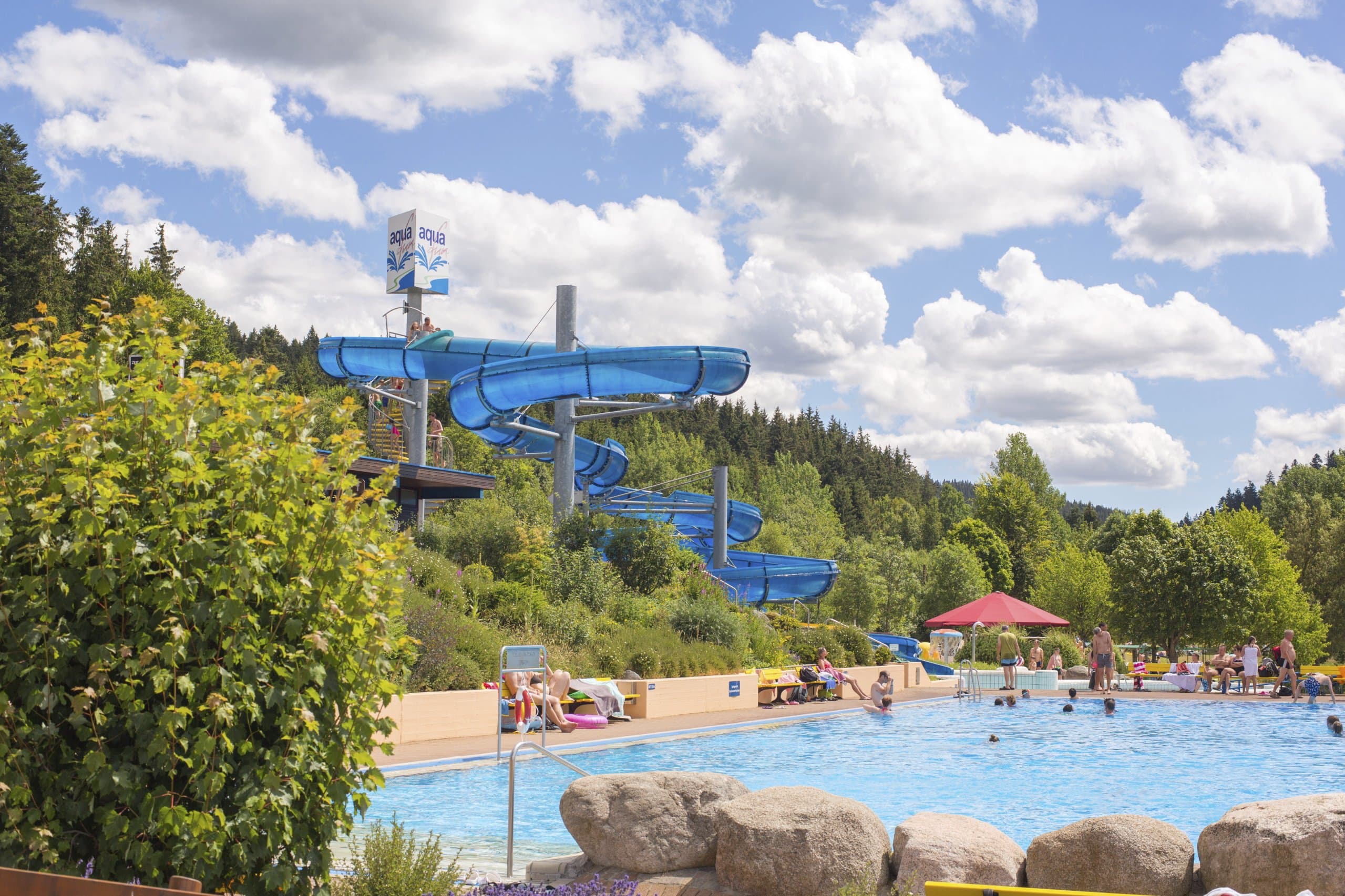 Blick auf das beheizte Schwimmerbecken. Im Hintergrund die blaue Rutsche.