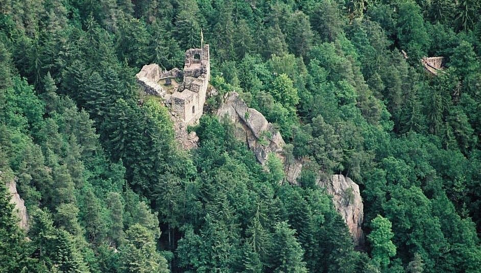In the picture, you can see an aerial photograph of the Hohenschramberg castle ruins surrounded by dense forests.