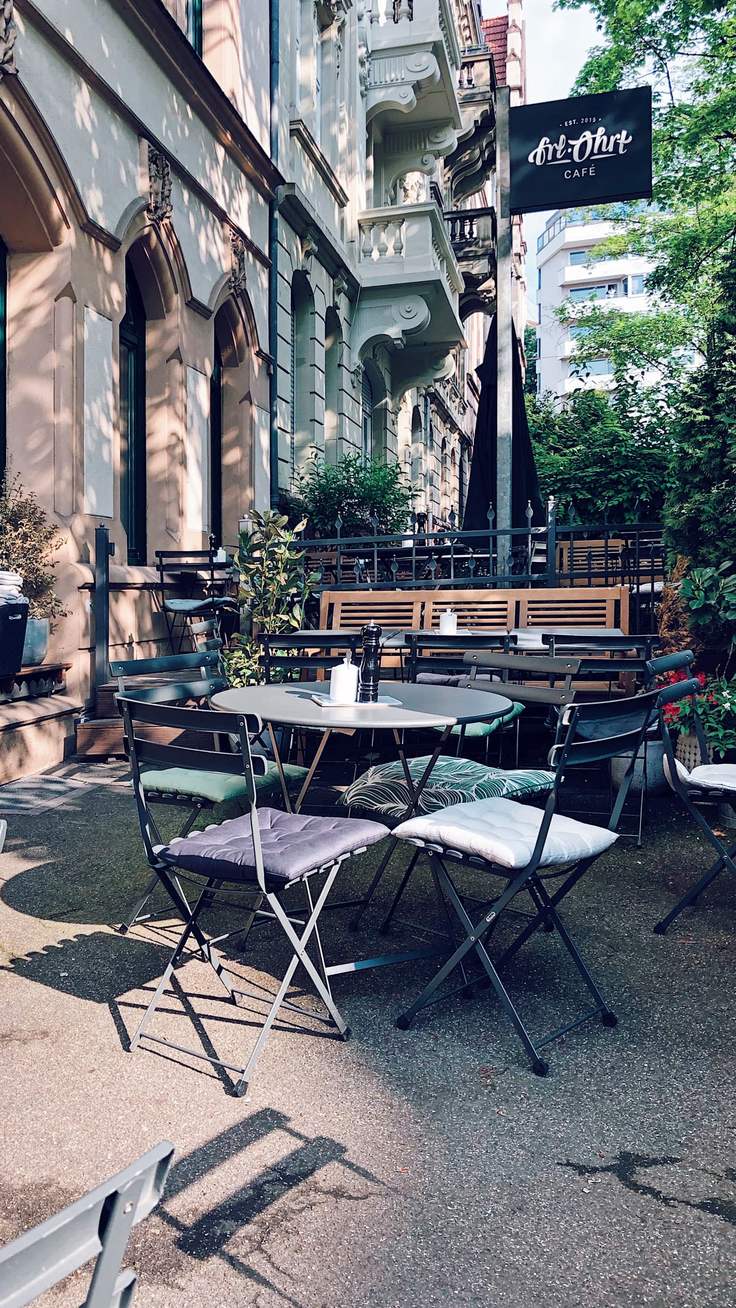 Außenansicht des Cafés mit der bestuhlten Terrasse und dem Fräulein Ohrt Schild an der Altbaufassade