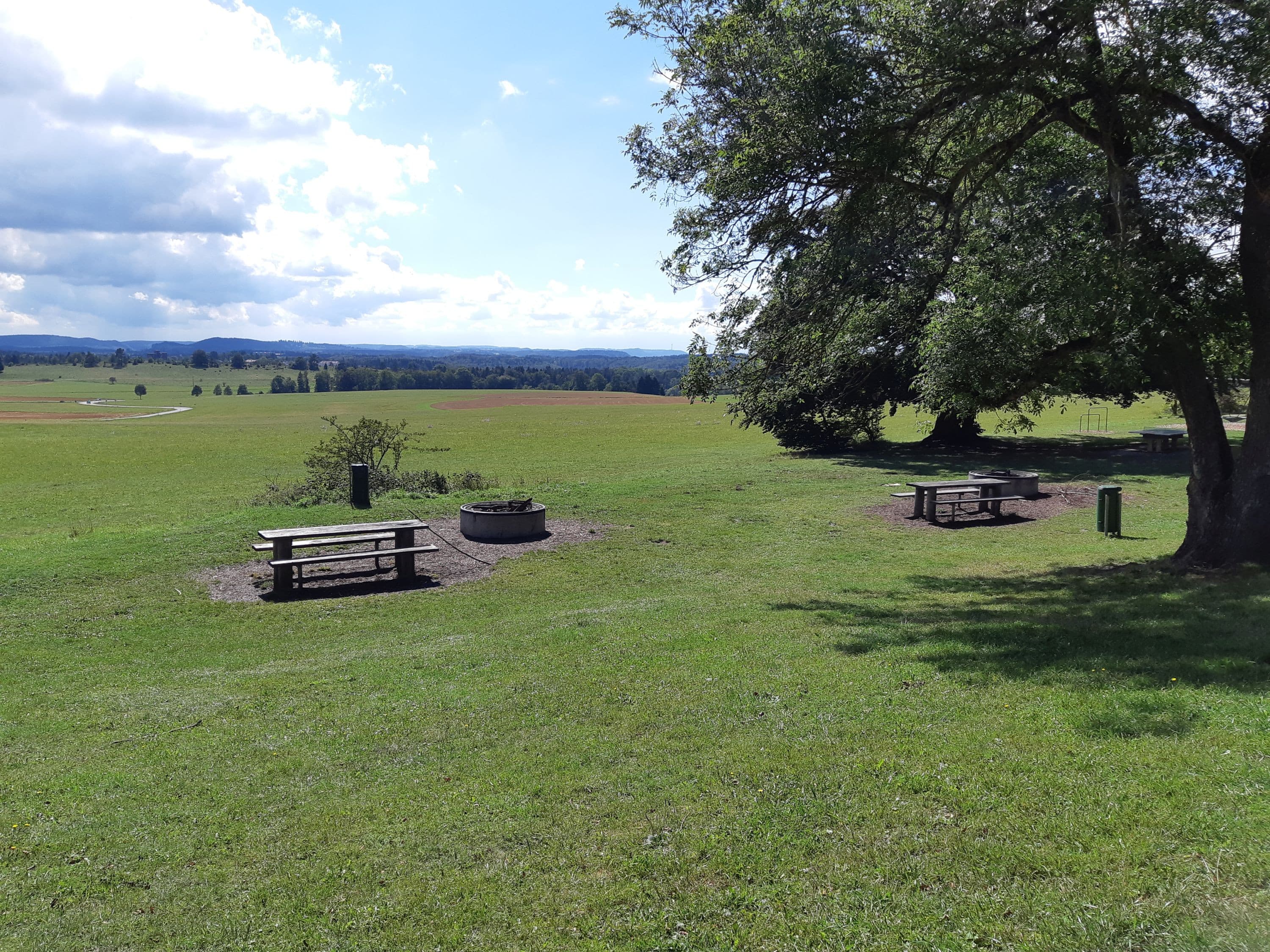 Grillstelle Schneckenbuckel auf großer Wiese mit Bänken und Tischen und Schatten spendenden Bäumen