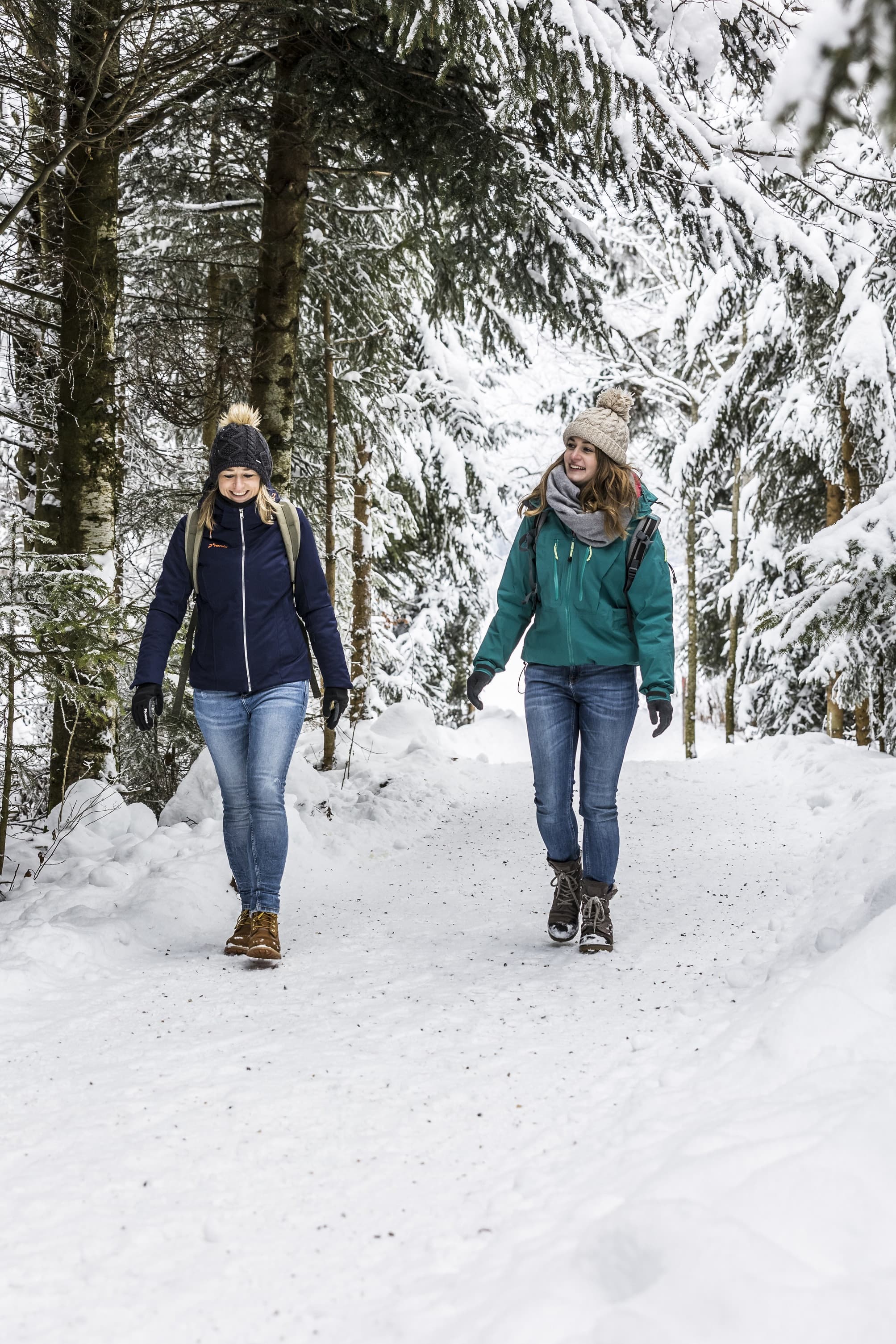 Zwei Frauen laufen durch einen verschneiten Wald