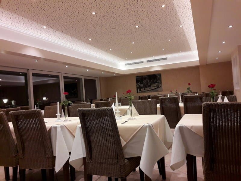 Innenansicht des Gastraumes mit vielen weißgedeckten Tischen.